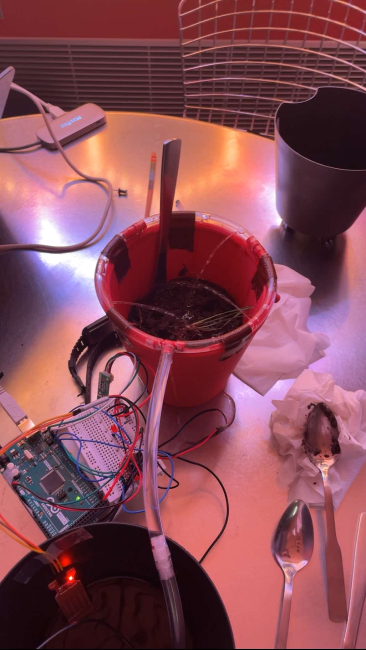 Arduino and breadboard wired to a moisture sensor and pump tubing for an early benchtop test